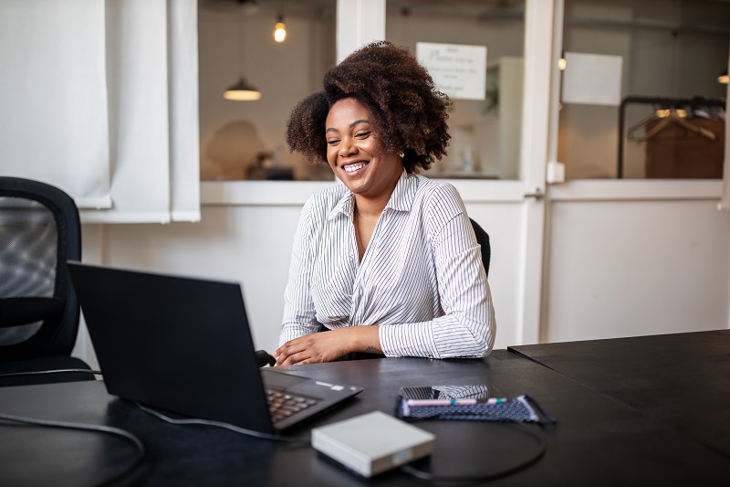 1248900587 Businessman sitting in office smiling during a video call. African woman on a video conference meeting at office.