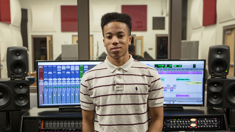 18-year-old Jaylen James stands in front of professional audio equipment at Stewarts Creek High. James also has a modest studio of his own, a collection of equipment and software he bought for himself with the money he earned working at a local restaurant.