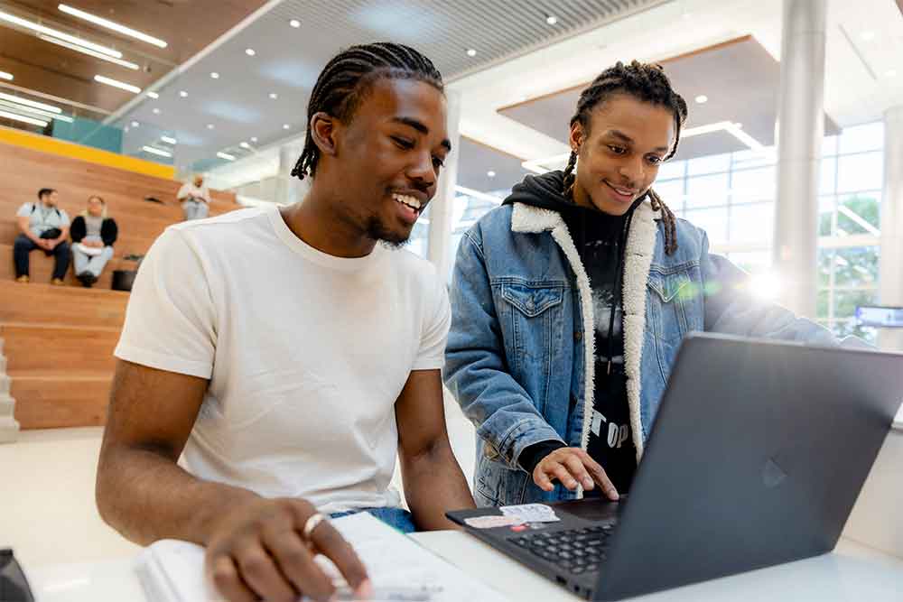 Two people conversing looking at the laptop