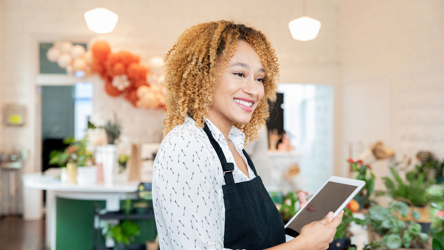 Woman Smiling while holding Digital Tablet and working in local plant store